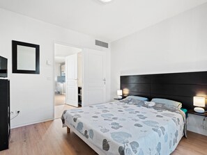 Ein Schlafzimmer mit einem Bett, Nachttischlampen, einem Spiegel und einer Tür zu einem Badezimmer.