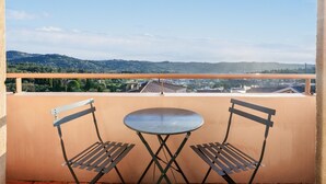 A balcony with two metal chairs and a small round table, overlooking a cityscape with distant hills. - Riviera Retreat in Grasse (Grasse)