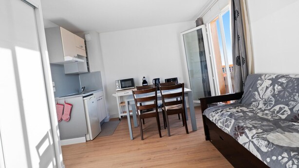 A compact room with a bed, a desk, a chair, a kitchenette, and a sliding glass door to the outside. - Riviera Retreat in Grasse (Grasse)