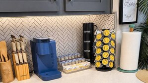 Eine Küche mit grauen Schränken, einer Kaffeemaschine, einem Wasserkocher und einer Kaffeemühle.