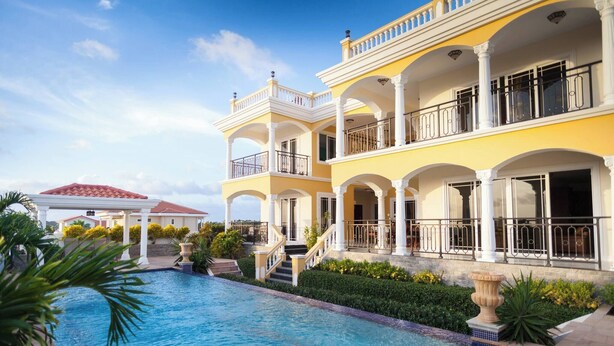 Ein mehrstöckiges Hotel mit Pool, Balkonen und einem gepflegten Garten.