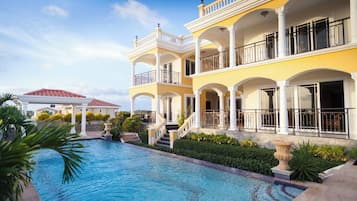 A multi-story hotel with a swimming pool, balconies, and a well-maintained garden.