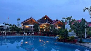 A hotel with a swimming pool, outdoor seating, and traditional architecture. - YKC FARMS AND VILLA (Siliguri)
