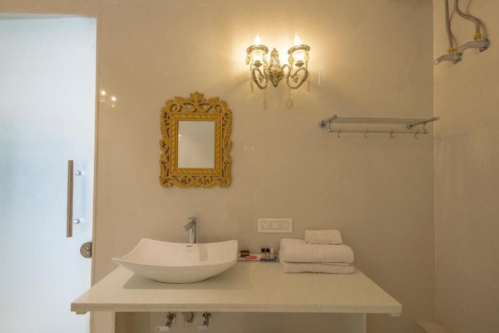 A bathroom with a white sink, a gold-framed mirror, and wall-mounted lights.