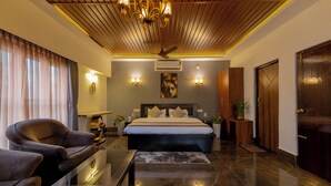 A modern bedroom with a large bed, a ceiling fan, and a nightstand with a lamp. - YKC FARMS AND VILLA (Siliguri)