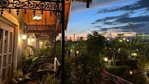 A wooden balcony with potted plants, a chair, and a view of the sky. - YKC FARMS AND VILLA (Siliguri)