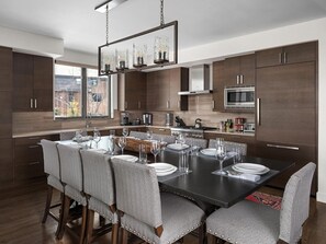 A modern kitchen with dark wood cabinets, a central island, and a hanging light fixture. - NEW! 6 Rolling Ridge 4-Bedroom Home with Mountain view (Big Sky)