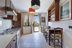 Une cuisine équipée d’une cuisinière, de placards et d’un coin repas avec des chaises et une table.
