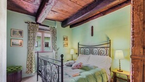 Ein Zimmer mit einem Bett, einem mit Vorhängen versehenen Fenster, einer Lampe und einer grünen Polsterbank.