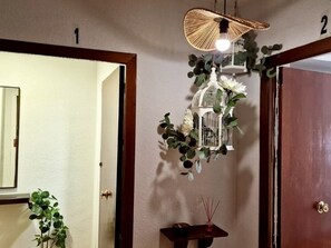A room with a wooden door, a white wall, a hanging light fixture, and a small table with a candle and incense sticks. - Spacious apartment in city center (Granada)