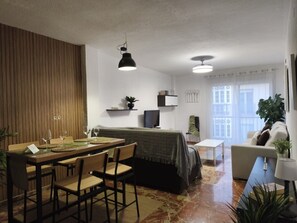 A modern living room with a dining area, a sofa, a TV, and a balcony with a view. - Spacious apartment in city center (Granada)
