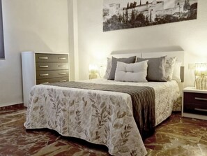 A bedroom with a bed, bedside tables, a dresser, and a wall-mounted picture. - Spacious apartment in city center (Granada)