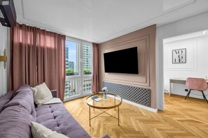 Ein modernes Wohnzimmer mit einem großen Fernseher, einer Couch, einem Couchtisch und einem Schreibtisch mit Stuhl.