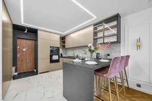 Eine moderne Küche mit Marmorarbeitsplatte, einem Einbauofen und einer Bar mit einer Blumenvase.