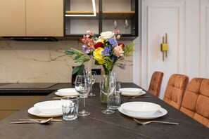 A dining table set with plates, glasses, and a vase of flowers. - Rondo ONZ Apt - 11th Floor, Air Con - by Rentujemy (Warszawa)