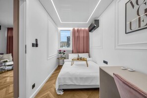 A modern bedroom with a bed, bedside table, and a window with curtains. - Rondo ONZ Apt - 11th Floor, Air Con - by Rentujemy (Warszawa)