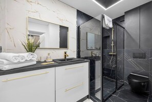 A modern bathroom with a marble vanity, a glass shower enclosure, and a black toilet. - Rondo ONZ Apt - 11th Floor, Air Con - by Rentujemy (Warszawa)