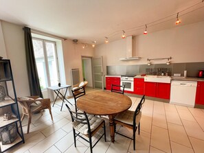 Eine moderne Küche mit roten Schränken, einem weißen Herd und einer Essecke mit einem Holztisch und Stühlen.