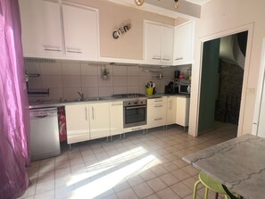 Eine moderne Küche mit weißen Schränken, einem Gasherd, einem Backofen, einer Spüle und einem Essbereich mit Tisch und Stühlen.