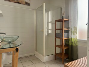 A bathroom with a glass sink, a wooden shelf, and a shower area. - Charming city center house - 8 guests (Port-Vendres)