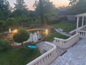 Ein Garten mit Teich, Statue und Laube.