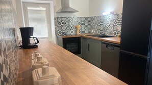 A kitchen with a wooden countertop, a black coffee maker, a dishwasher, and a refrigerator. - Cottage by the water - 8 guests (Chérancé)