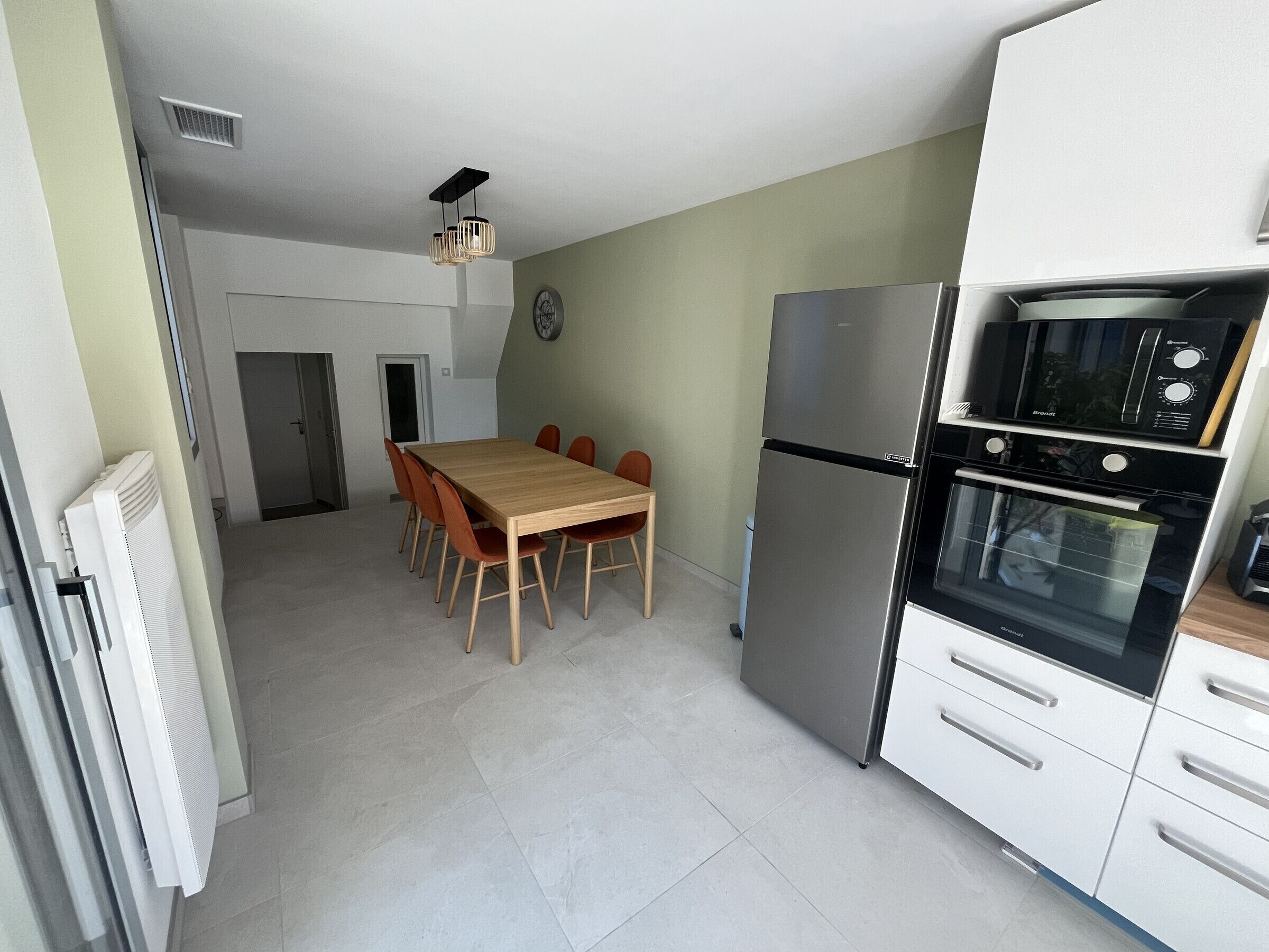 Una cocina compacta con una mesa de comedor, sillas, un refrigerador y un horno.