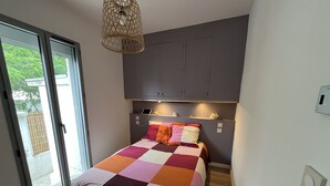 A bedroom with a bed, a bedside table, a lamp, a window, and a door. - Air-conditioned house near beach - 6 guests (Argelès-sur-Mer)