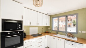 A modern kitchen with white cabinets, a black microwave, an oven, and a dishwasher. - Air-conditioned house near beach - 6 guests (Argelès-sur-Mer)