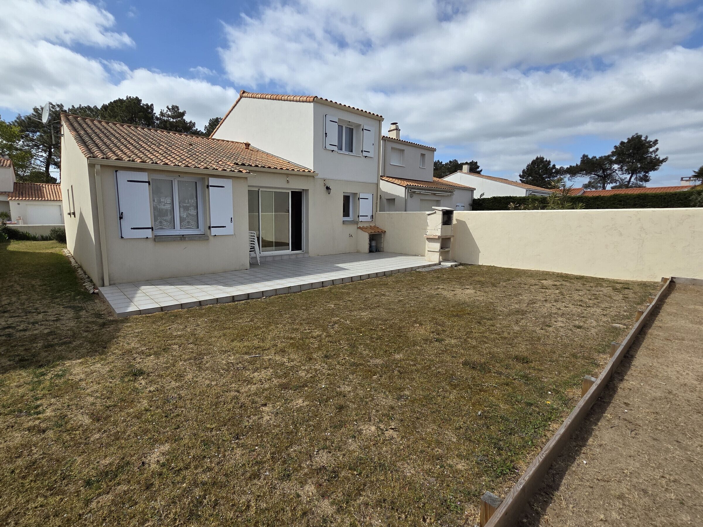 A two-story house with a tiled roof, a front door, and a small patio area.