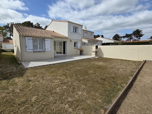 A two-story house with a tiled roof, a front door, and a small patio area.