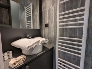 Ein modernes Badezimmer mit Waschbecken, Handtuchhalter und Pflegeprodukten.