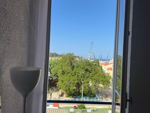 Ein Zimmer mit Blick auf eine Baustelle, Bäume und einen Kran.