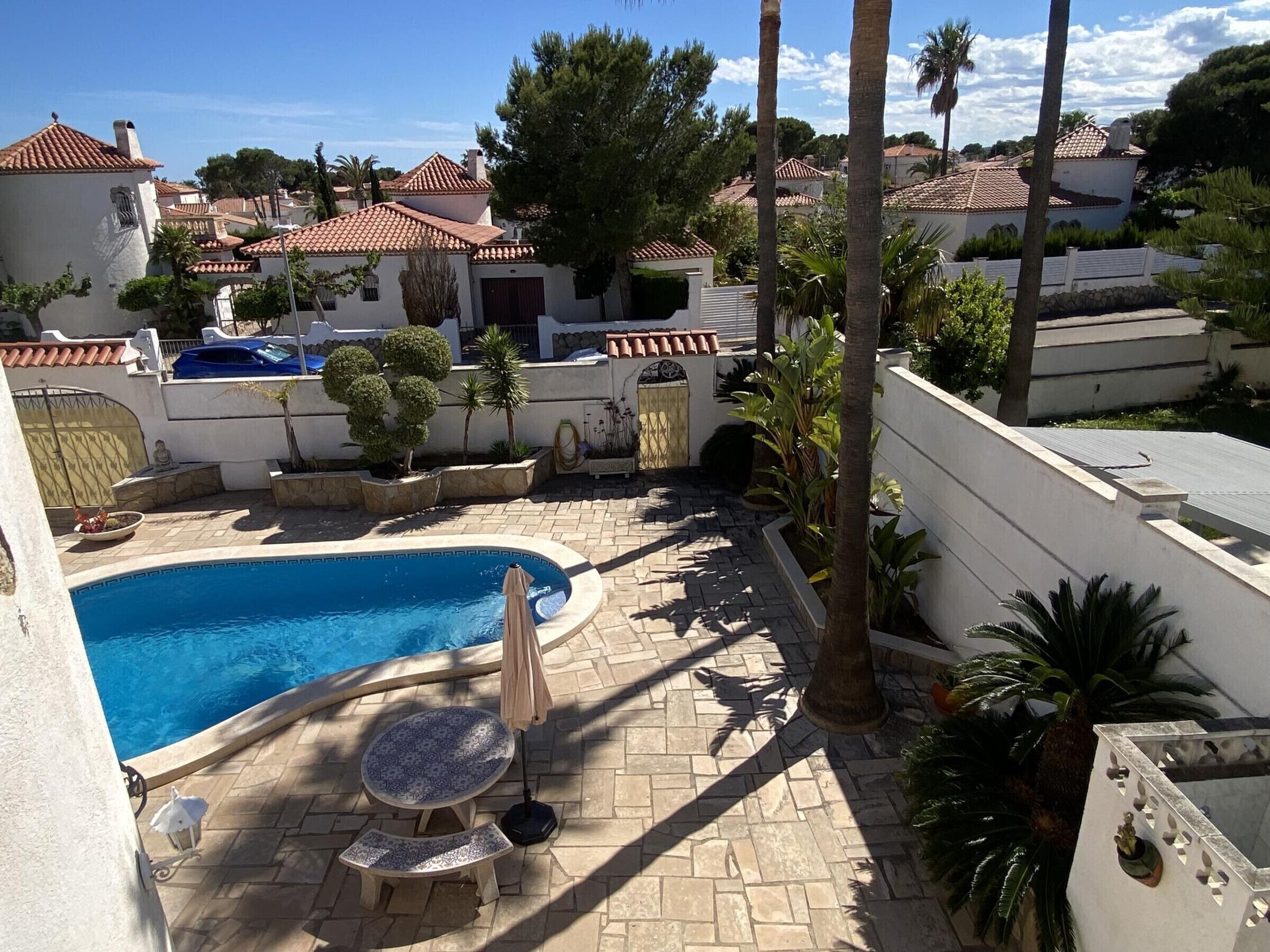 A swimming pool with a tiled deck, a small round table, and a chair.