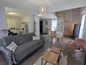 Ein modernes Wohnzimmer mit einer Couch, einem Esstisch, Stühlen und einer Treppe.
