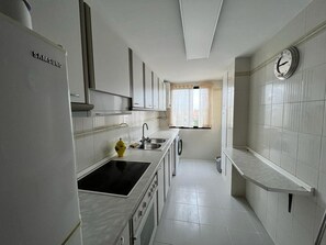 Eine moderne Küche mit weißen Schränken, einem Backofen, einem Spülbecken und einem Fenster mit Vorhängen.