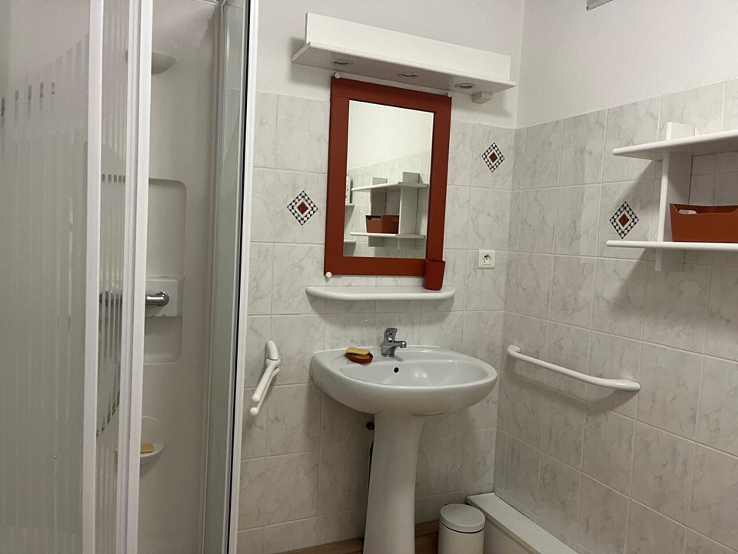 Une salle de bain avec un lavabo blanc, un miroir et un porte-serviettes.