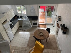 A kitchen with white cabinets, a microwave, a sink, and a hanging light fixture. - Family house 150m from the beach - 7 guests (Capbreton)