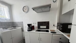 Eine moderne Küche mit weißen Schränken, einer eingebauten Mikrowelle, einer Kaffeemaschine und einer Uhr an der Wand.