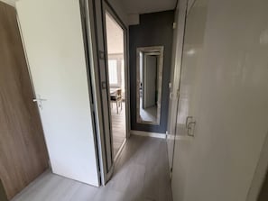 Ein Flur mit einer Holztür, einer weißen Tür und einem Spiegel an der Wand.