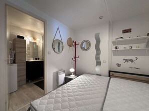 Ein Schlafzimmer mit Bett, Kleiderschrank, Spiegel, Kleiderständer und einer Ablage mit Dekoration.