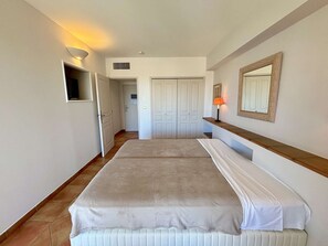 A hotel room with a bed, a bedside table, a lamp, a mirror, and a wardrobe. - Calm apartment with AC - 4 guests (Saint-Cyr-sur-Mer)