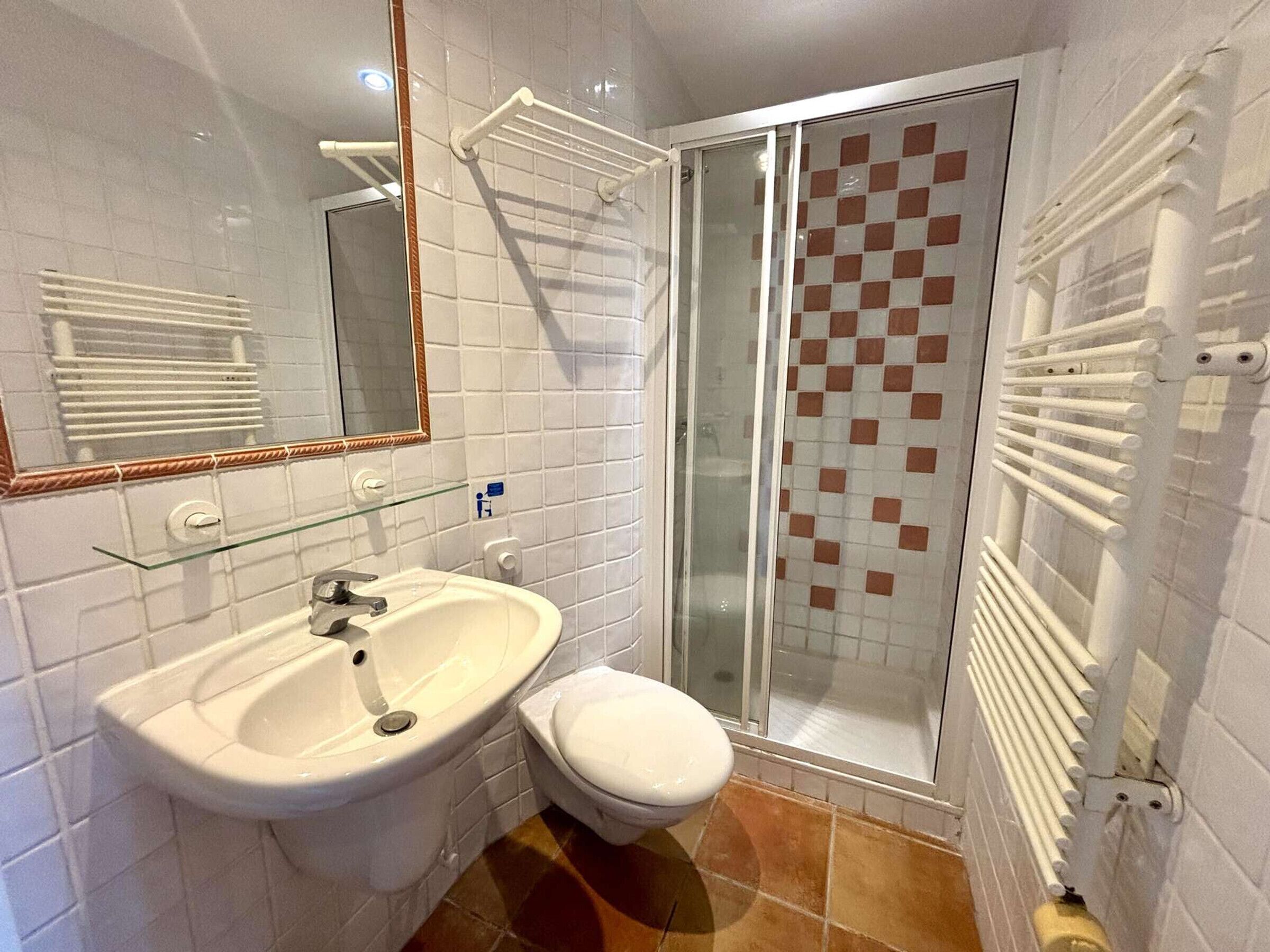 A bathroom with a white sink, toilet, and glass shower enclosure.