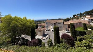 Un quartier résidentiel avec des maisons à étages, un ciel dégagé et une vue lointaine sur la mer.