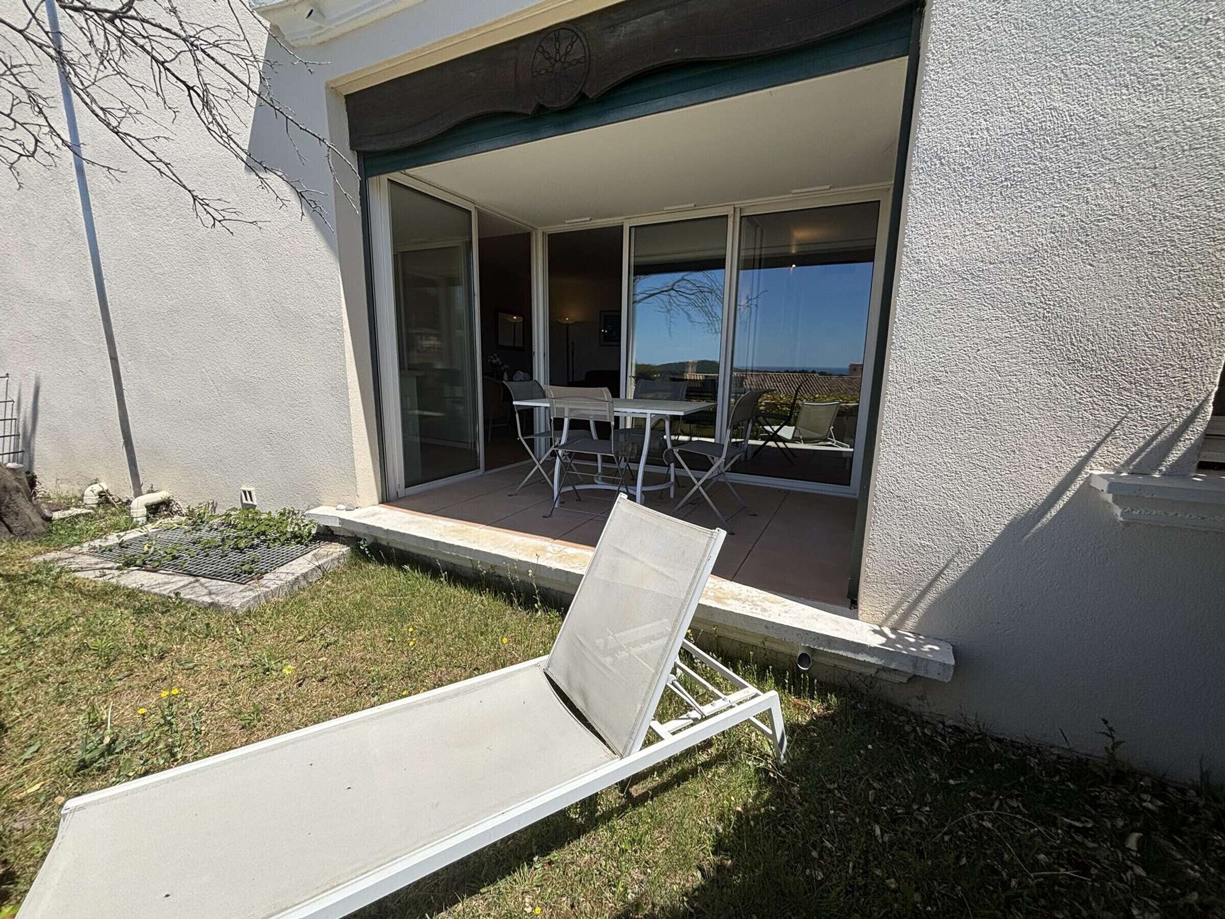 Eine Terrasse mit einer Lounge-Liege, einem Tisch und Stühlen.