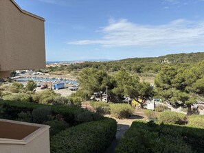 A view of a marina with boats, a sign for 'Grand Hotel', and surrounding greenery. - Apartment with sea view - 4 guests (Fleury-Saint-Pierre-la-Mer)