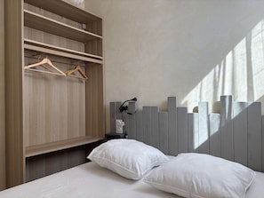 A bedroom with a wooden wardrobe, a bedside table with a lamp, and a white bed with pillows. - Apartment with sea view - 4 guests (Fleury-Saint-Pierre-la-Mer)