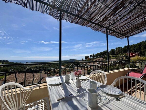 Eine Terrasse mit Esstisch, mit Blick auf eine schöne Landschaft.