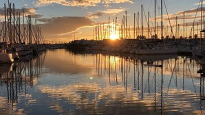 A marina with multiple boats docked, calm water, and a sunset in the background. - Studio in port center, parking - 2 guests (Cap d'Agde)