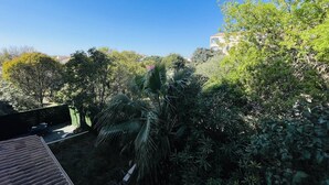 A residential area with dense vegetation, a clear blue sky, and a building in the background. - Studio in port center, parking - 2 guests (Cap d'Agde)